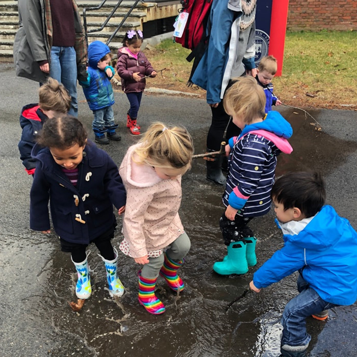 group of kids jumping in rain puddles