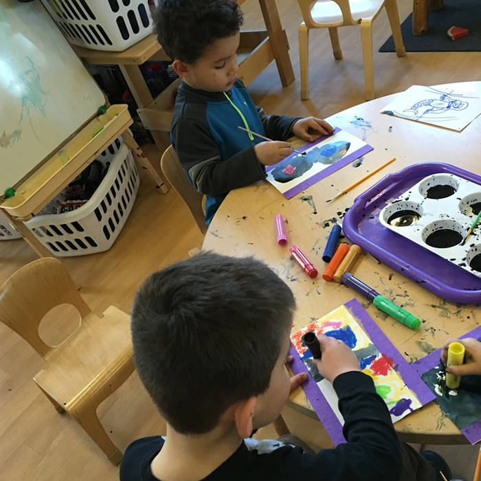 boys painting together in classroom