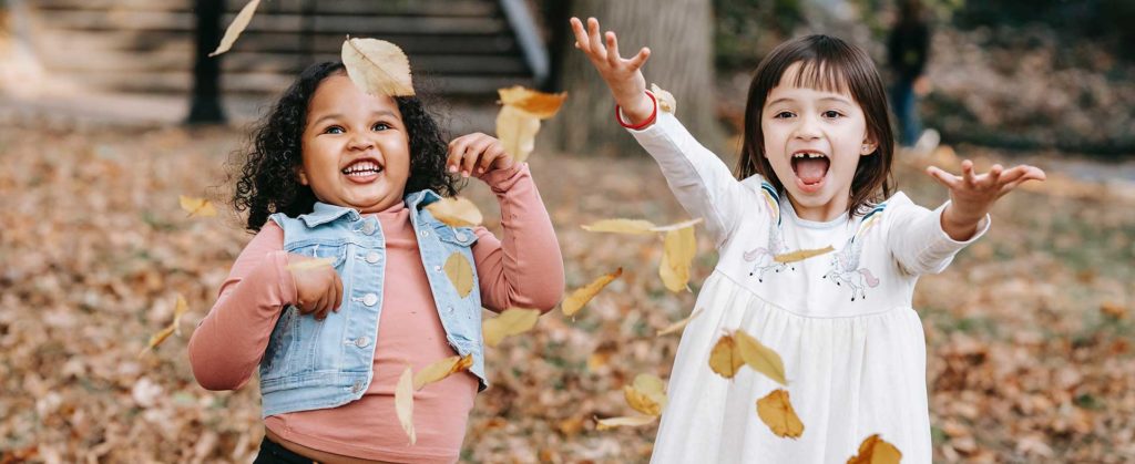 smiling girls playing in leaves