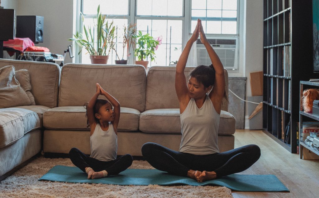 mother and child in a yoga pose in living room