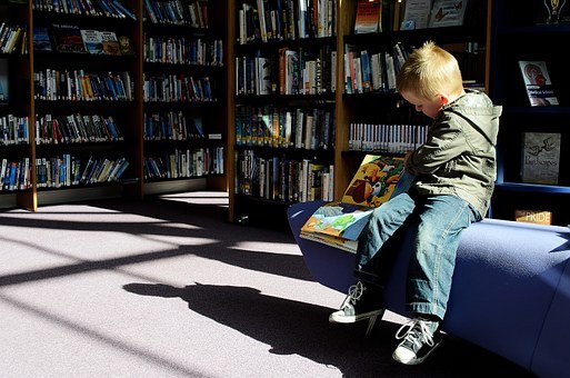 young boy reading a book at library