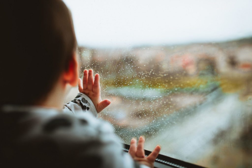 boy looking out rainy window