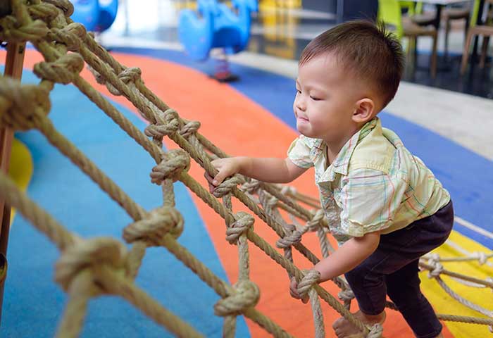 physical development image 3-4 year old Asian child climbing rope latter in gym
